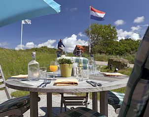 Sunny terrace of Grand Hotel Opduin - Holiday home A, De Koog, Texel, overlooking nature and Dutch flag.