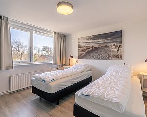 Tweede slaapkamer in De Zandduyn vakantiehuis, De Koog, Texel, met twee eenpersoonsbedden en serene sfeer.