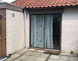 Zonnig terras bij Kamerstraat 39, vakantiehuis in De Koog, Texel met schuifdeur en kleurrijke bloemen.