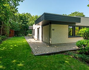 Zijaanzicht van vakantiehuis 16 - Zeebries in De Koog, Texel, omgeven door groen op de Waddeneilanden.