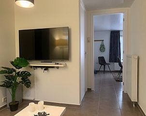 Gerumiges Wohnzimmer im Familienbungalow, De Koog, Texel mit TV und Blick auf das Esszimmer.