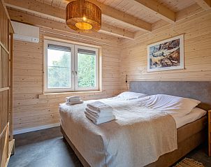 Slaapkamer met houten interieur in De Verleegen Hoek vakantiehuis in De Koog Texel met uitzicht op natuur.