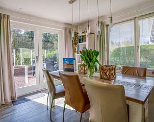 Essecke im Ferienhaus Honeysuckle 91, De Koog, Texel, mit Blick auf den Garten und Zugang zur Terrasse.