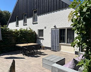 Geniet van de zon op het ruime terras van vakantiehuis Stormvogel in De Koog, Texel, met comfortabele zitplaatsen en groene omgeving.