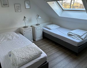 Comfortabele slaapkamer met twee bedden in Stormvogel, vakantiehuis in De Koog, Texel, met veel natuurlijk licht en moderne inrichting.