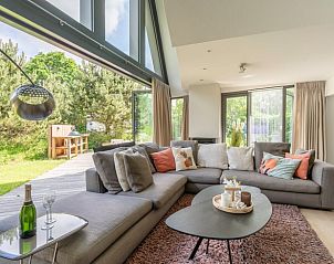 Gemtliches Wohnzimmer im Ferienhaus in De Koog, Texel, mit groen Fenstern und Blick auf die Natur, perfekt fr Entspannung auf den Watteninseln.