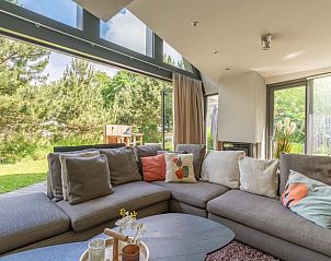 Blick aus dem Wohnzimmer des Ferienhauses in De Koog, Texel, mit grnem Garten und gemtlichen Sitzecken, ideal fr einen ruhigen Urlaub.