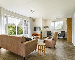 Geniet van de zon op het terras van Villapark Vogelmient, 4-persoons villa in De Koog, Texel, met uitzicht op een groene tuin.