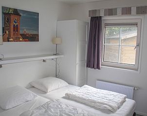 Slaapkamer met uitzicht in 't Langebosch vakantiehuis, Dennenbos, Texel voor een serene vakantie op de Waddeneilanden.