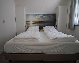 Comfortabele slaapkamer met tweepersoonsbed in Nieuwlanderweg 75 vakantiehuis, De Koog, Texel, met een rustgevend stranddecor.