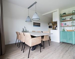 Stijlvolle eetruimte in Nieuwlanderweg 75 bungalow, De Koog, Texel, met een grote eettafel en decoratieve elementen.