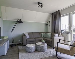 Gezellige woonkamer met uitzicht op de tuin in Nieuwlanderweg 75 bungalow, De Koog, Texel, ideaal voor ontspannen avonden.