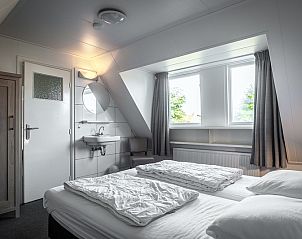 Lichte slaapkamer in Vakantiehuis De Heggemus, Den Burg, Texel met groot raam en moderne meubels.
