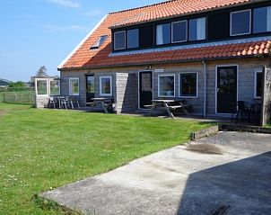 Buitenkant van Vakantiehuis Weidezicht in Den Burg, Texel met zonnig terras en groene omgeving op de Waddeneilanden.