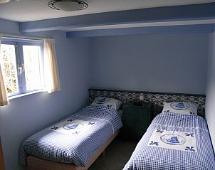 Sfeervolle slaapkamer van De Pimpelmees, vakantiehuis in Den Burg, Texel, met twee comfortabele bedden.