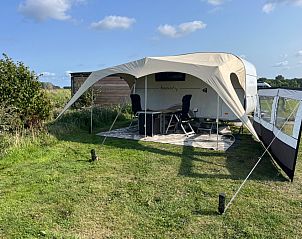 Caravan Beachy Don Voorzorg in Den Burg, Texel met zonnige veranda en groene omgeving.