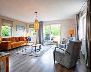 Gemtliches Wohnzimmer im Ferienhaus in Den Burg, Texel, mit moderner Einrichtung und Blick auf den grnen Garten.