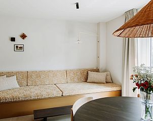 Lichte woonruimte in Luxe Appartement 4p, Den Burg, Texel met comfortabele bank en moderne inrichting.