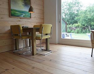 Eethoek in Zeealsem vakantiehuis, Ballum, Ameland met houten vloer en uitzicht op de tuin.