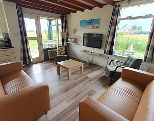 Gezellige woonkamer van bungalow Weizicht in Dennenbos, Texel met uitzicht op de natuur.