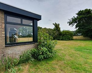 Zijaanzicht van bungalow Weizicht, Dennenbos, Texel met groene tuin en bomen.