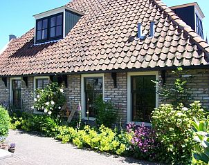 Charmant exterieur van Appartement De Merel in Den Burg, Texel, met traditionele dakpannen en groene tuin.