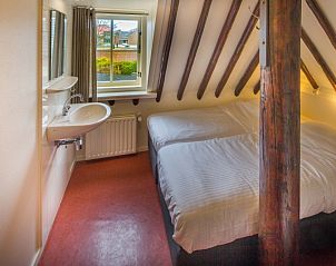 Knusse slaapkamer met houten balken in Appartement De Merel, Den Burg, Texel, met uitzicht op de tuin.