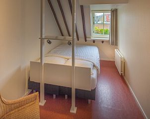 Lichte slaapkamer in Appartement De Merel, Den Burg, Texel, met groot raam en comfortabele bedden.