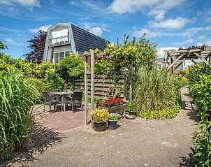 Zonnig terras bij Appartement De Merel, Den Burg, Texel, met zitgelegenheid en kleurrijke planten.
