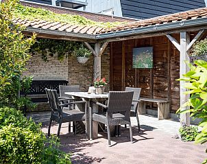 Rustieke zithoek buiten bij Appartement De Merel, Den Burg, Texel, met houten overkapping en groene omgeving.