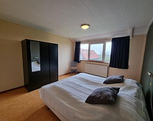 Ruime slaapkamer met groot raam in Vakantiehuis Westzicht, Den Burg Texel, voor een ontspannen verblijf.