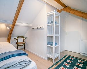 Knusse slaapkamer in Stadhuisje Texel, Den Burg, Texel met houten details en zachte beddengoed op de Waddeneilanden.