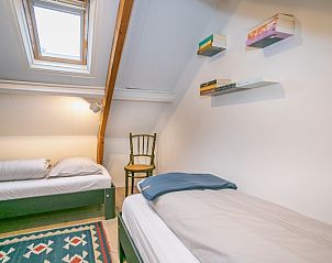 Gezellige slaapruimte in Stadhuisje Texel, Den Burg, Texel met dakraam en boekenplanken voor een huiselijke sfeer.