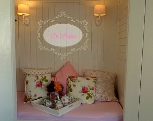 Gezellige zithoek in De Bedstee, vakantiehuis in Den Burg, Texel met kussens en sfeerverlichting.