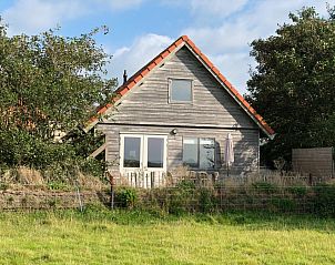 Vakantiehuis Duinzicht in Den Burg, Texel, biedt een charmante houten gevel met uitzicht op de groene natuur van de Waddeneilanden.