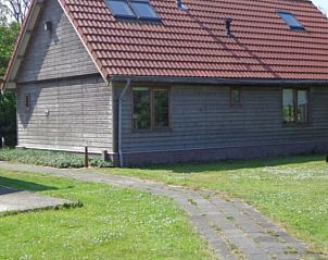 Zijaanzicht van Vakantiehuis Duinzicht in Den Burg, Texel, met een uitnodigend pad en een ruim grasveld.