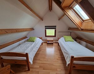 Zolderkamer in Vakantiehuis Duinzicht, Den Burg, Texel, met twee eenpersoonsbedden en een dakraam voor natuurlijk licht.