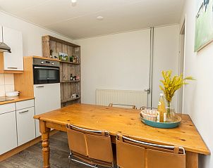 Dining area in vacation home Sil in Den Hoorn, Texel with wooden table and open kitchen.