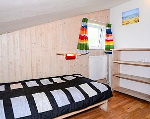 Sfeervolle slaapkamer in De Kievit vakantiehuis Den Hoorn Texel met kleurrijke gordijnen.