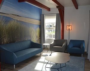 Gemtliches Wohnzimmer im Ferienhaus in Den Hoorn, Texel, mit bequemen Sitzgelegenheiten und einem schnen Naturthema.