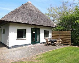 Gezellig vakantiehuis Nieuwlanderweg 69 met rieten dak in De Koog, Texel, omringd door groen en een ruim terras.