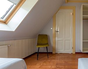 Zolderkamer in Vakantiehuis Oosterend Texel met dakraam en comfortabele stoelen, perfect voor een ontspannen verblijf.