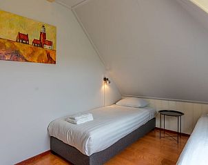 Slaapkamer op zolder in Vakantiehuis Oosterend Texel met kunstwerk aan de muur, ideaal voor een sfeervol verblijf.
