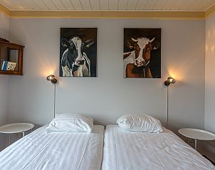 Slaapkamer in Gouden Rijder vakantiehuis, Oosterend, Texel, met comfortabele bedden en kunst aan de muur.