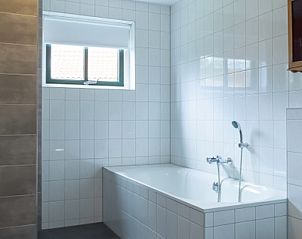 Moderne badkamer in Type III - nr. 21B Fazant, vakantiehuis Texel, met ligbad en strakke tegels.