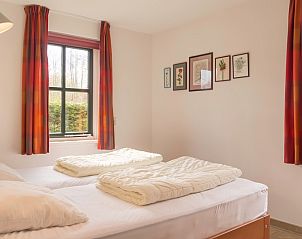 Slaapkamer in Type III - nr. 21B Fazant, vakantiehuis Oosterend Texel, met tweepersoonsbed en kleurrijke gordijnen.