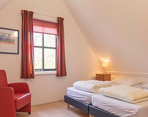 Lichte slaapkamer in Type III - nr. 21B Fazant, vakantiehuis Oosterend Texel, met comfortabele bedden en rode stoel.