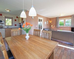 Essecke im Ferienhaus 8690 - Junier - Huisman, Sd-Eierland, Texel, mit Holztisch und Blick auf die grne Umgebung.