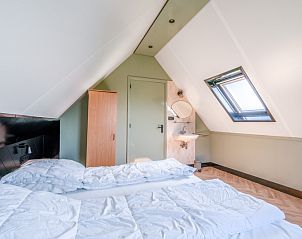 Gemtliches Mansardenzimmer im Ferienhaus De Vijf Sterren Zuid-Eierland Texel mit Dachfenster und Bett.