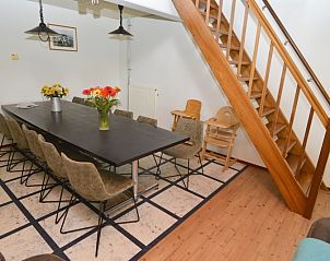 Essecke im Ferienhaus De Oorsprong, Zuid-Eierland, Texel mit langem Tisch und Treppe zum Obergeschoss.